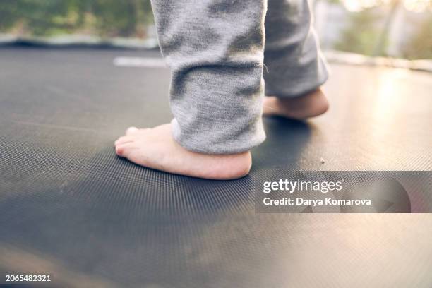 close up foot of the boy. toddler is jumping on a trampoline outside. childhood, entertainment for a child. lifestyle photo with copy space. - extreem weer stock pictures, royalty-free photos & images