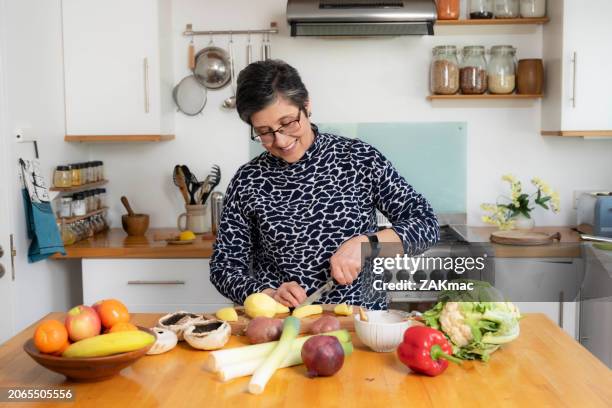 woman peeling potatoes, preparing a meal in a domestic kitchen. stock photo. - chopping food stock pictures, royalty-free photos & images