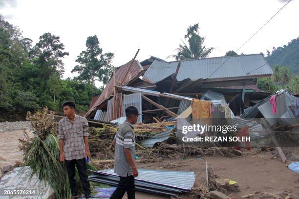 Villagers stand near a damaged house by a river after a flash flood at Pesisir Selatan in West Sumatra on March 10, 2024. The death toll from flash...