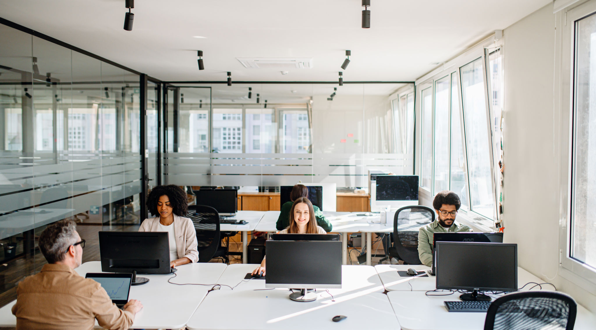 In a spacious and bright office, a diverse team is focused on individual tasks In a spacious and bright office, a diverse team is focused on individual tasks
