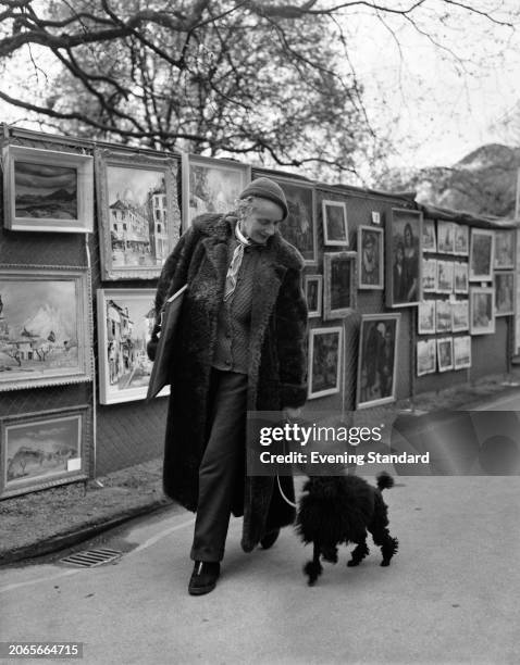 Irish artist Sine MacKinnon and her poodle visiting an open-air art exhibition at Victoria Embankment Gardens in London, May 9th 1955.