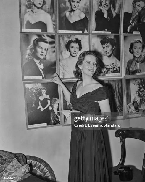 English actress Patricia Cutts pointing at a photographic portrait of herself, September 29th 1953. Her portrait is displayed alongside those of...