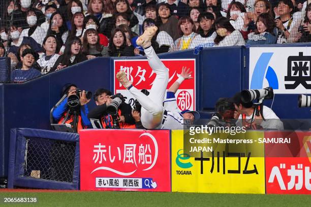 Infielder Martin Muzik of Team Europe falls into a photographers pit as he fails to catch a foul fly of Infielder Takaya Ishikawa of Samurai Japan in...
