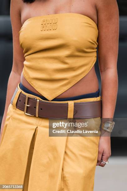 Paola Locatelli wears yellow Miu Miu sleeveless top, matching skirt, brown belt, gold bracelet, outside Miu Miu, during the Womenswear Fall/Winter...