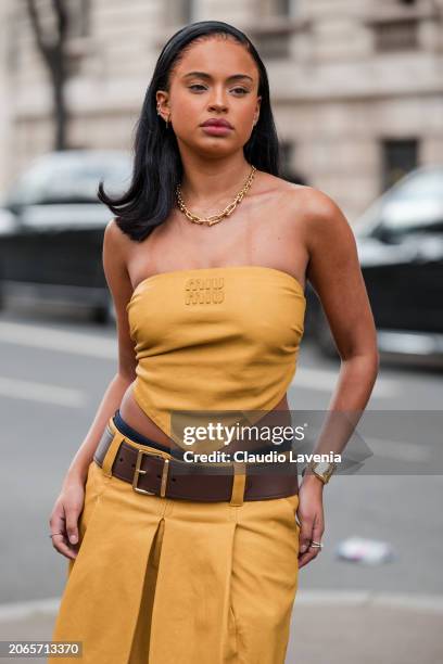 Paola Locatelli wears yellow Miu Miu sleeveless top, matching skirt, brown belt, gold bracelet, outside Miu Miu, during the Womenswear Fall/Winter...