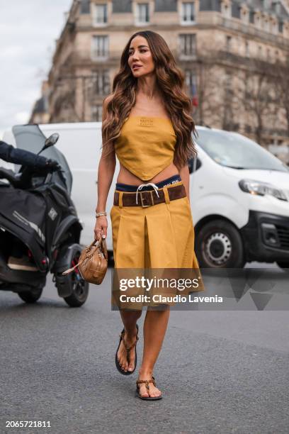 Tamara Kalinic wears yellow Miu Miu sleeveless top, matching skirt, blue Miu Miu underwear, brown belt, beige Miu Miu bag, brown sandals, outside Miu...