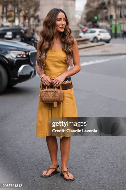 Tamara Kalinic wears yellow Miu Miu sleeveless top, matching skirt, blue Miu Miu underwear, brown belt, beige Miu Miu bag, brown sandals, outside Miu...