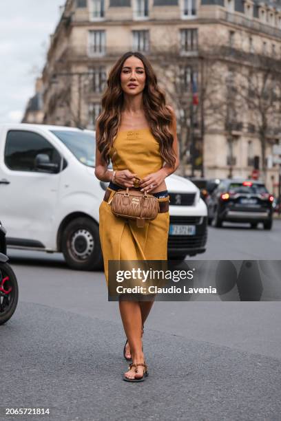 Tamara Kalinic wears yellow Miu Miu sleeveless top, matching skirt, blue Miu Miu underwear, brown belt, beige Miu Miu bag, brown sandals, outside Miu...