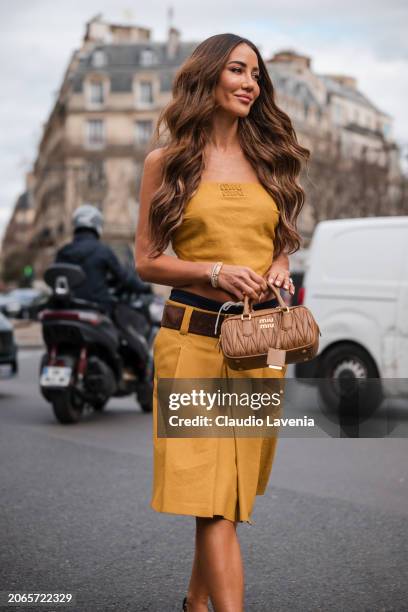 Tamara Kalinic wears yellow Miu Miu sleeveless top, matching skirt, blue Miu Miu underwear, brown belt, beige Miu Miu bag, brown sandals, outside Miu...