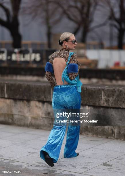 Alexandra Kaiser is seen wearing blue velvet pants with a silver chain around her chest, a leopard printed top with long sleeves and turtle neck,...