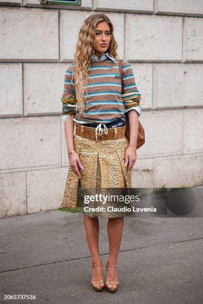 Emili Sindlev wears brown and blue striped t-shirt, gold skirt, brown belt, brown bag, gold sandals, outside Miu Miu, during the Womenswear...