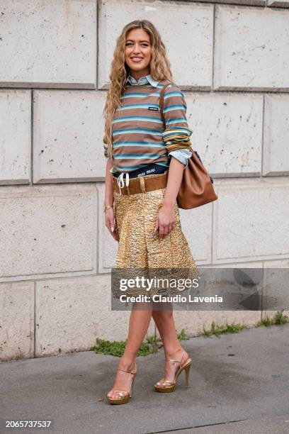 Emili Sindlev wears brown and blue striped t-shirt, gold skirt, brown belt, brown bag, gold sandals, outside Miu Miu, during the Womenswear...