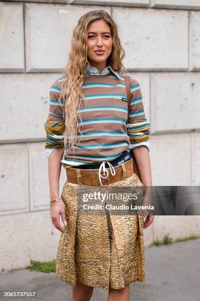 Emili Sindlev wears brown and blue striped t-shirt, gold skirt, brown belt, brown bag, outside Miu Miu, during the Womenswear Fall/Winter 2024/2025...