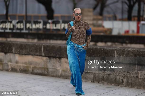 Alexandra Kaiser is seen wearing blue velvet pants with a silver chain around her chest, a leopard printed top with long sleeves and turtle neck,...