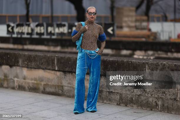 Alexandra Kaiser is seen wearing blue velvet pants with a silver chain around her chest, a leopard printed top with long sleeves and turtle neck,...