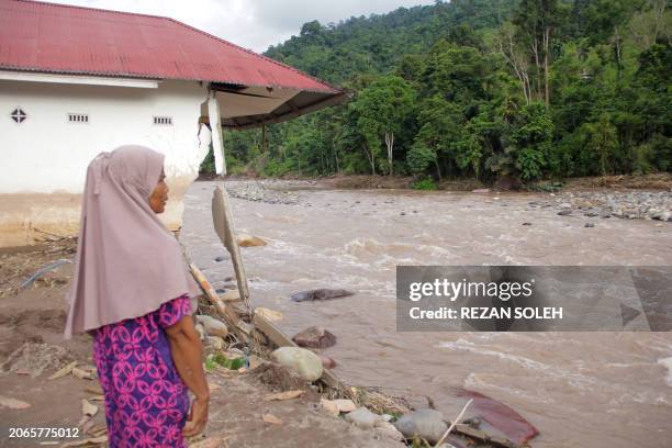 Woman stands near a damaged house by a river after a flash flood at Pesisir Selatan in West Sumatra on March 10, 2024. The death toll from flash...