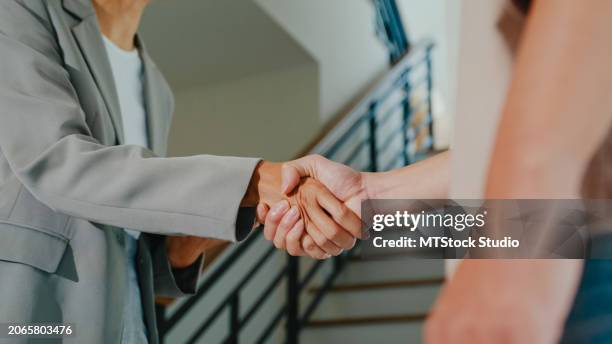 close-up of asian female real estate agent handshaking after complete agreement with tenants after showing new houses. landlord selling real estate to happy couple customer for investment. - landlord stock pictures, royalty-free photos & images