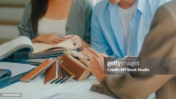 nahaufnahme von asiatischen mietern, die farben, muster und materialien auswählen und sie der innenarchitektin für das neue haus geben. glückliches paar kauft immobilien als investition. - stoffmuster stock-fotos und bilder