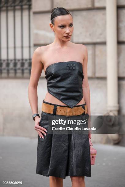 Guest wears black Miu Miu leather sleeveless top, matching leather skirt, brown belt, outside Miu Miu, during the Womenswear Fall/Winter 2024/2025 as...