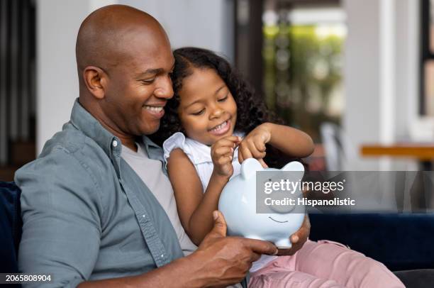 padre e hija ahorrando dinero en una alcancía - plan financiero fotografías e imágenes de stock