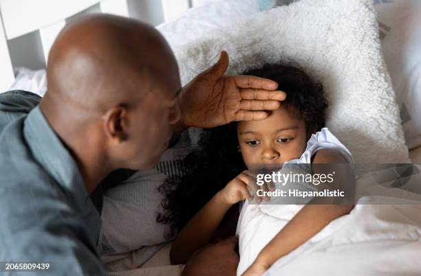 father checking on his sick daughter at home - fever stock pictures, royalty-free photos & images