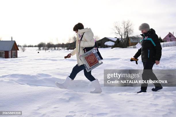 Members of a local election commission with a ballot box walk upon their arrival on Volkostrov Island in Lake Onega, Republic of Karelia, during...