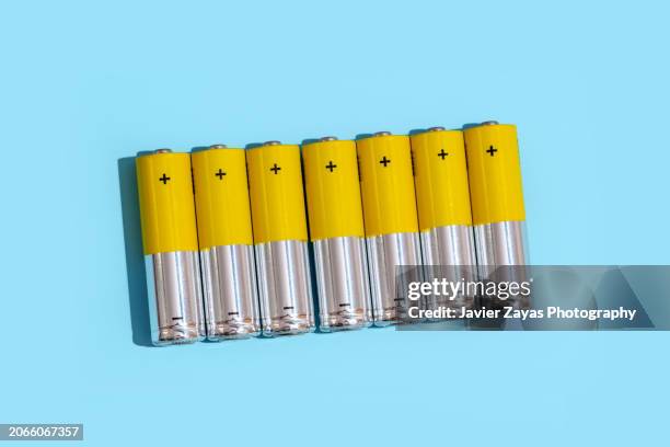 yellow batteries on light blue background - yellow light effect stock pictures, royalty-free photos & images