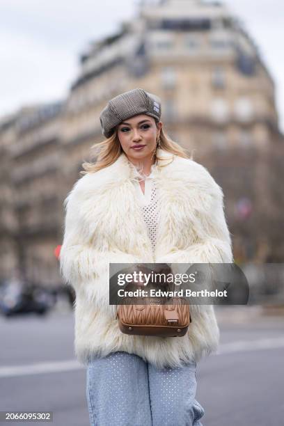 Merve Gorgotz wears a beret hat, a white oversized fluffy faux fur coat , a mesh polo shirt, a brown leather bag, outside Miu Miu , during the...