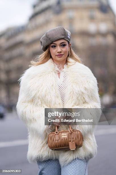 Merve Gorgotz wears a beret hat, a white oversized fluffy faux fur coat , a mesh polo shirt, a brown leather bag, outside Miu Miu , during the...