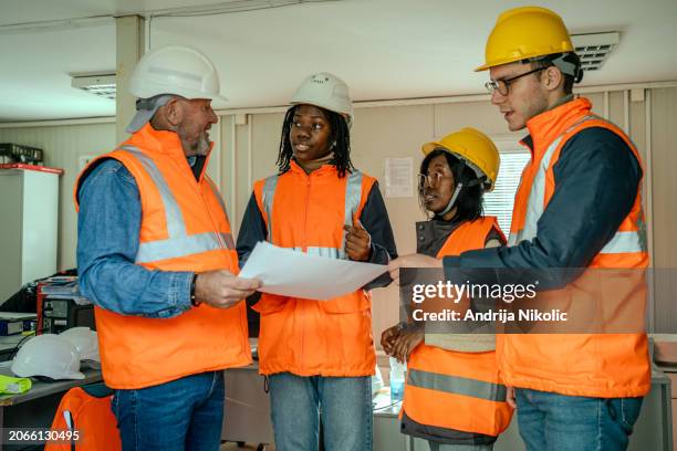 joyful construction team reviewing plans - tijdelijk gebouw stockfoto's en -beelden