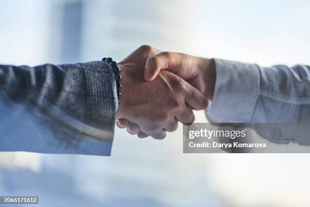 hands on a business meeting. two hands: a man in a jacket with a bracelet and a man in a white shirt are shaking each other. handshake, the concept of a business arrangement with copy space. - fusies en overnames stockfoto's en -beelden