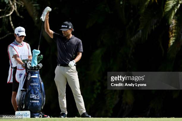 Satoshi Kodaira of Japan waits with his caddie before playing his shot from the fourth tee during the first round of the Puerto Rico Open at Grand...