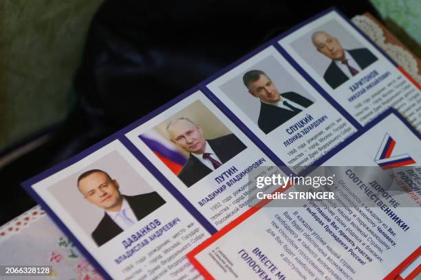 Leaflet displaying presidential candidates is seen on a table as local residents vote in their apartment during early voting for Russia's...