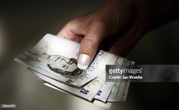 Woman clutches a handful of Sterling notes June 9 in London. The Chancellor of the Exchequer, Gordon Brown, is expected today to announce whether...