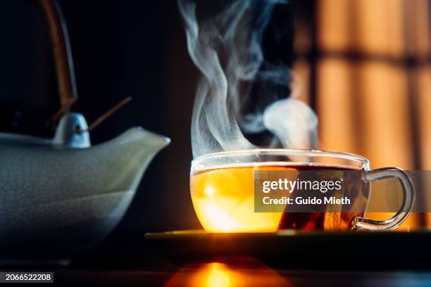 a glass cup of hot tea on a table. - thé photos et images de collection