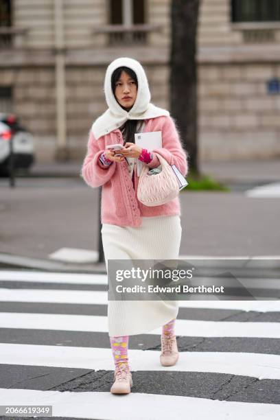 Guest wears a balaclava, a pink cardigan, a white skirt , floral print tights, sneakers shoes, outside Miu Miu , during the Womenswear Fall/Winter...