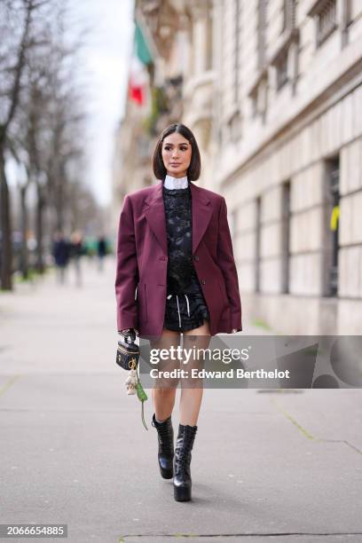 Heart Evangelista wears hair pins, a white shirt, a burgundy oversized blazer jacket , a black floral print mini dress , a black leather bag , high...