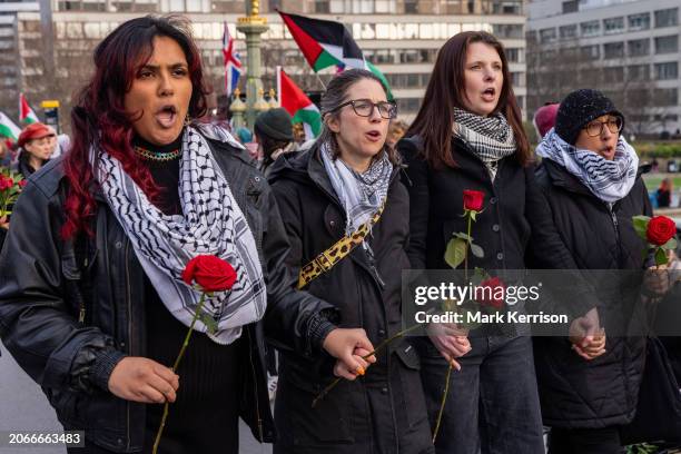 Women wearing keffiyehs and holding red roses take part in an International Women's Day action organised by groups including Parents for Palestine,...