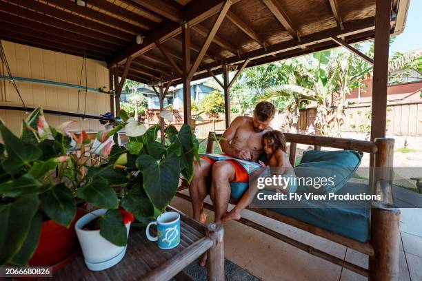 father reading with toddler daughter on lanai of vacation rental in hawaii - lanai stock pictures, royalty-free photos & images