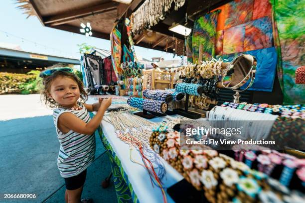 toddler girl shopping for souvenirs while on tropical vacation - hawaii souvenir stock pictures, royalty-free photos & images