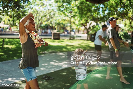Active senior couple taking hula class in park with granddaughter Active senior couple taking hula class in park with granddaughter