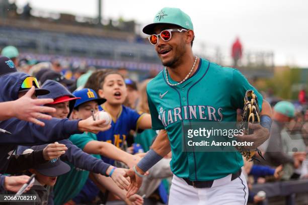 Julio Rodriguez of the Seattle Mariners slaps hands with fans on his way to the dugout before a spring training game against the Los Angeles Angels...