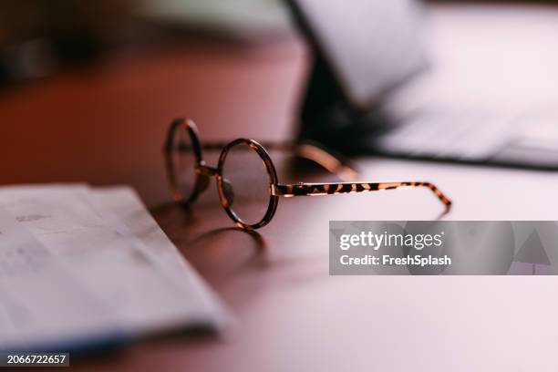 focused close-up of elegant eyeglasses on business desk workspace - reading glasses stock pictures, royalty-free photos & images