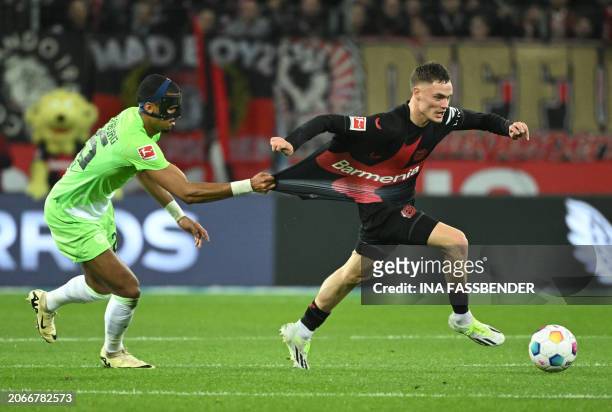 Wolfsburg's German defender Moritz Jenz pull the shirt of Bayer Leverkusen's German midfielder Florian Wirtz during the German first division...