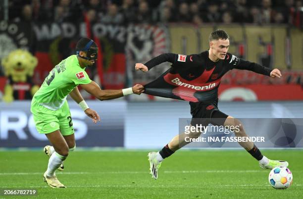 Wolfsburg's German defender Moritz Jenz pull the shirt of Bayer Leverkusen's German midfielder Florian Wirtz during the German first division...