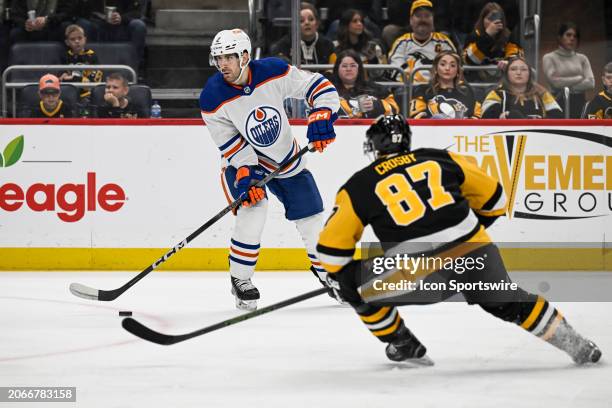 Edmonton Oilers defenseman Evan Bouchard passes the puck against Pittsburgh Penguins center Sidney Crosby during the second period in the NHL game...