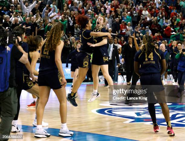 Hannah Hidalgo and Anna DeWolfe of the Notre Dame Fighting Irish celebrate with teammates following their 55-51 victory against the NC State Wolfpack...