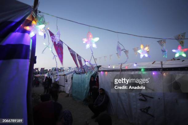 Palestinian children make Ramadan lanterns out of paper and hang them at their makeshift tents during the holy month of Ramadan in Deir Al Balah,...