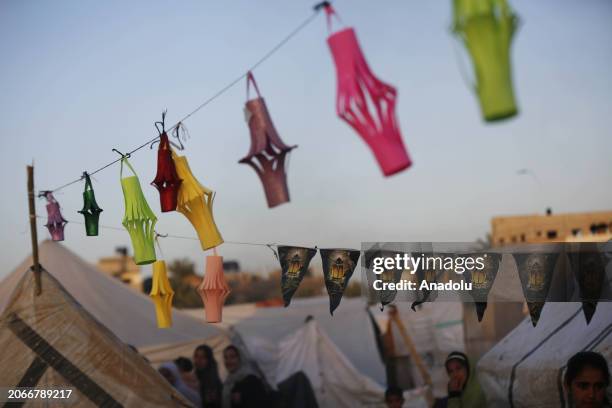 Palestinian children make Ramadan lanterns out of paper and hang them at their makeshift tents during the holy month of Ramadan in Deir Al Balah,...