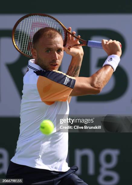 Dan Evans of Great Britain plays a backhand against Roman Safiullin in their first round match during the BNP Paribas Open at Indian Wells Tennis...